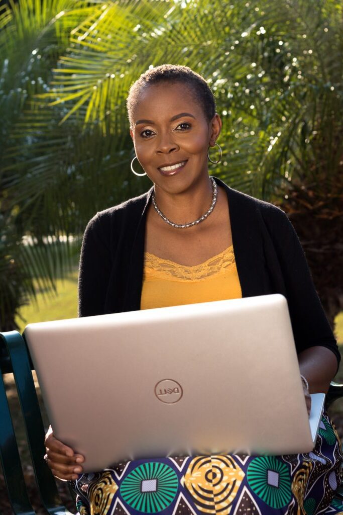 Caribbean VA Coach smiling and holding a laptop
