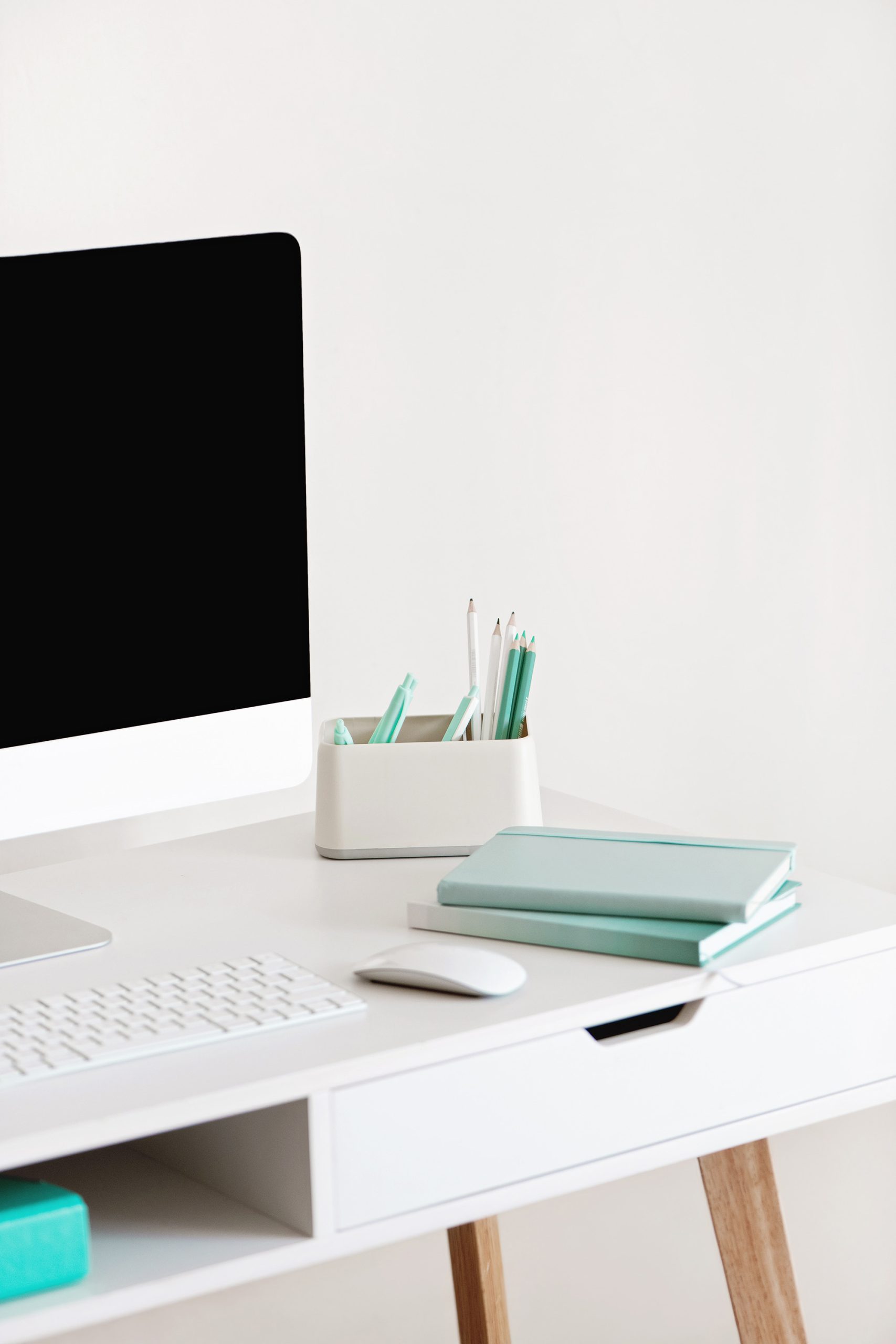 white office desk with laptop and turquoise books