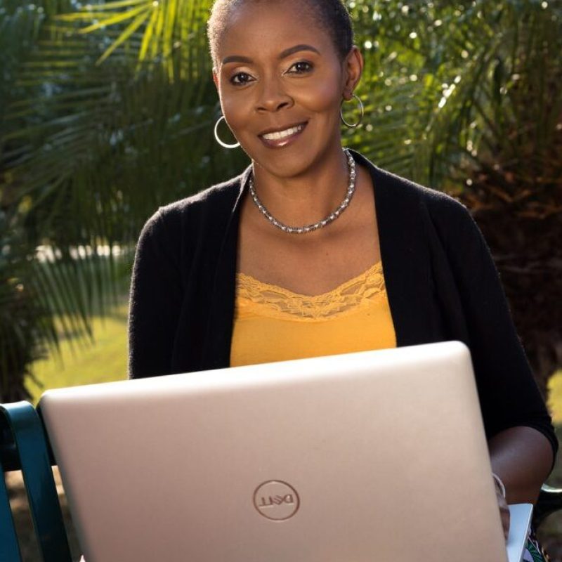Caribbean VA Coach smiling and holding a laptop