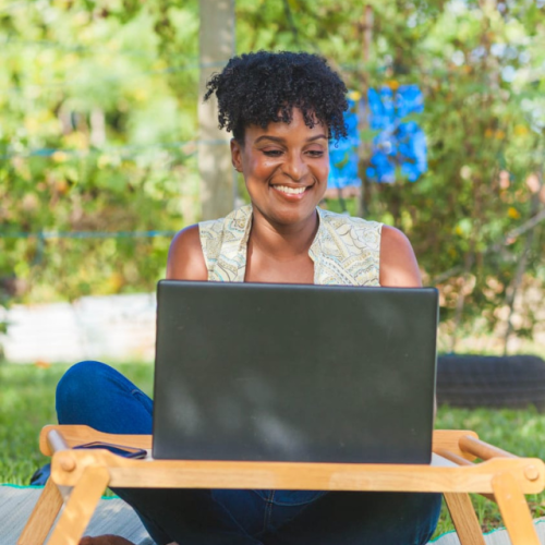virtual assistant sitting with her laptop on the grass
